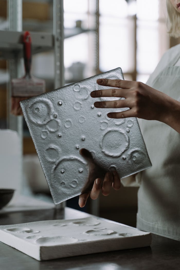 Glass artisan crafting a textured glass piece in a workshop environment, showcasing expert craftsmanship.